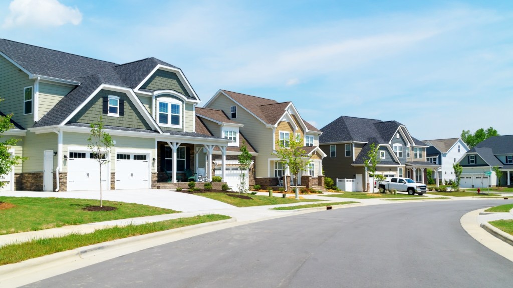 A street of new suburban homes with lawns and driveways.