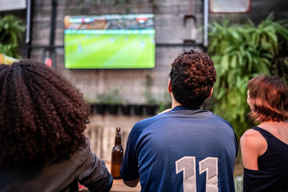 Group of people watching a sports event on TV.