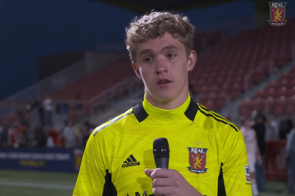 Jeffrey Dewsnup holding a microphone while wearing a yellow Real Monarchs soccer jersey.