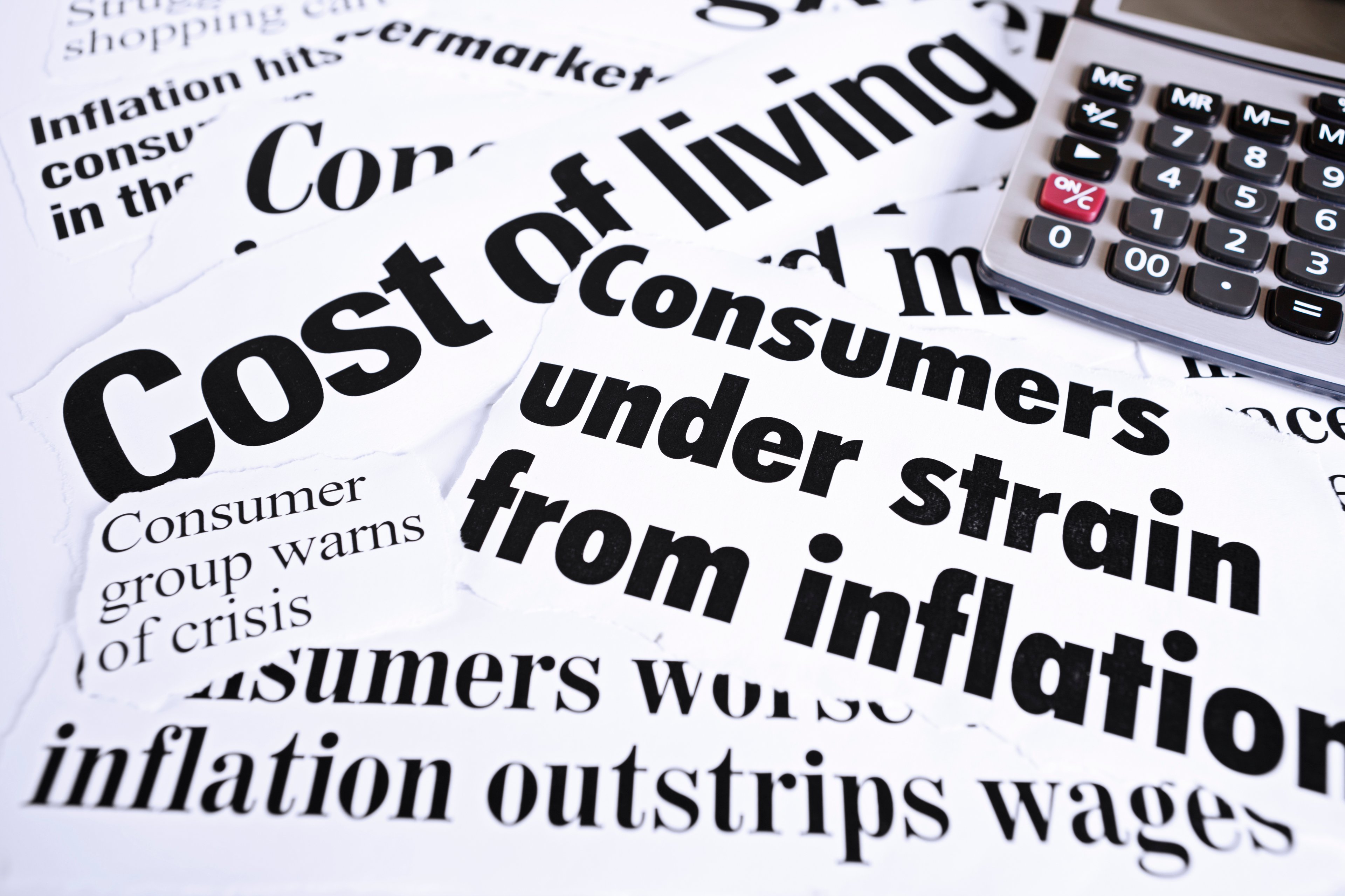 A calculator set next to several newspaper clippings highlighting rapidly rising inflation. 