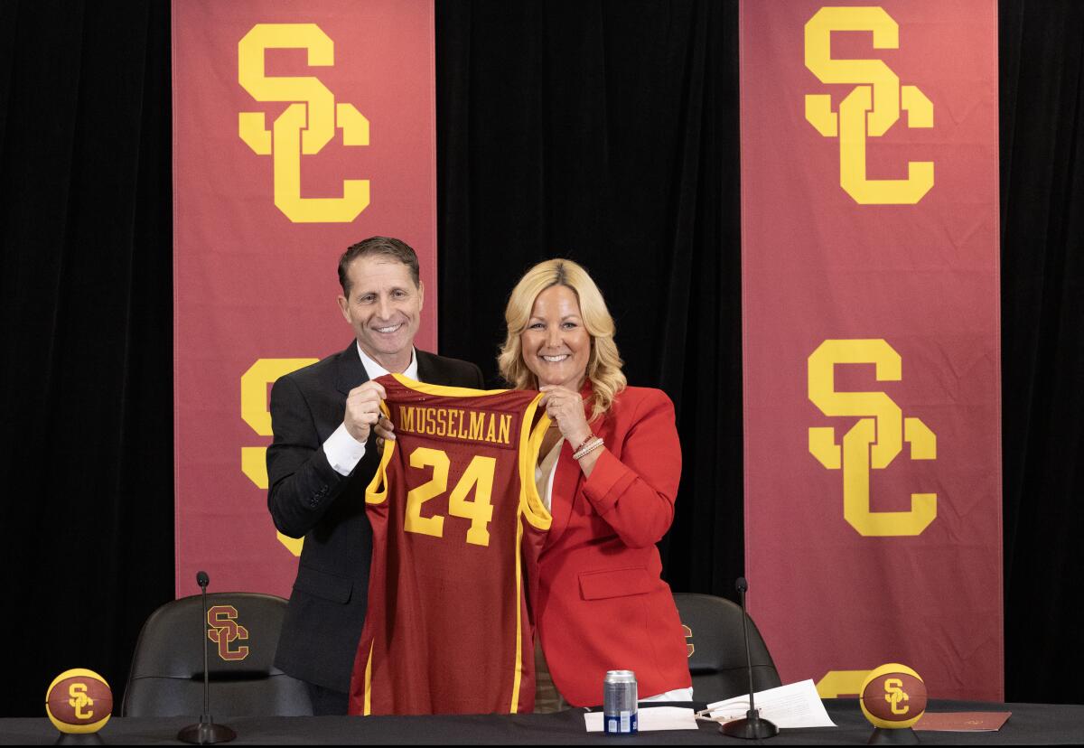 Eric Musselman, left, and Jennifer Cohen hold a jersey with Musselman's name as he's introduces as Trojans' basketball coach.