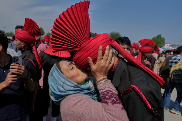 The mother of a newly graduated soldier of the Jammu and Kashmir Light Infantry (JKLI) Regiment kisses her son during a graduation parade at a training center on the outskirts of Srinagar, Indian controlled Kashmir, Saturday, May 30, 2026. (AP Photo/Mukhtar Khan)