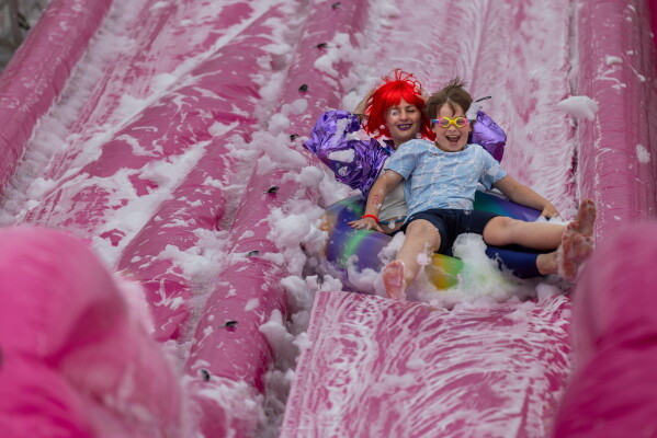 Visitors slide down a water slide into a giant soup bowl during the Pink Soup Fest in Vilnius, Lithuania, Saturday, May 30, 2026. (AP Photo/Mindaugas Kulbis)