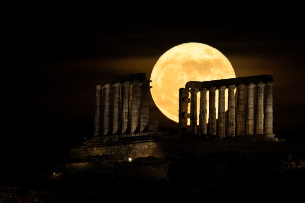 The full moon rises behind the ancient temple of Poseidon at Cape Sounion, Greece, on Sunday, May 31, 2026. (AP Photo/Yorgos Karahalis)