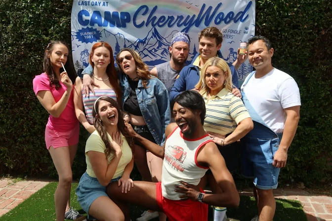 A group of nine people looking at the camera in front of a sign that reads "Camp Cherrywood."