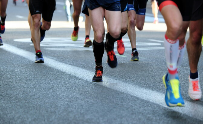 Several pairs of running legs on asphalt.