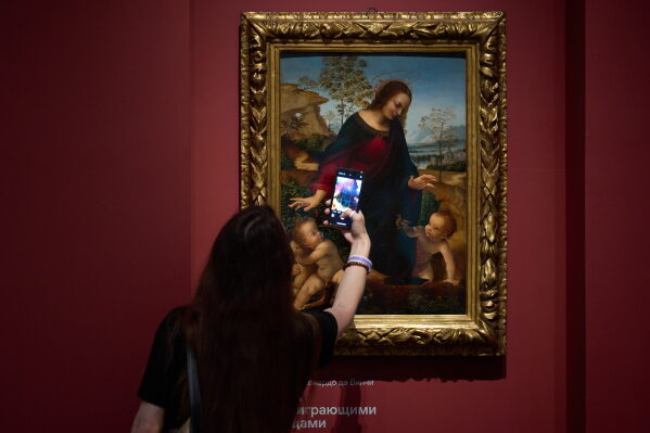 A visitor takes a photo of the painting "Madonna with Two Playing Infants" by a Leonardo da Vinci follower at the first in the series of solo exhibitions "Renaissance Madonnas, from Private Collections"at the Pushkin State Museum of Fine Arts, in Moscow, Russia, Tuesday, June 2, 2026. (AP Photo/Alexander Zemlianichenko)