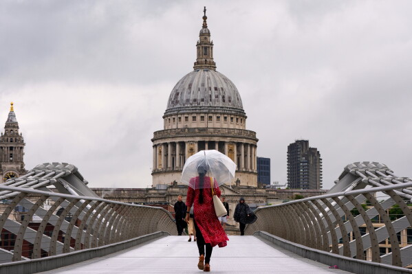 A pedestrian holds an umbrella as she walks over the Millennium Bridge in London, Tuesday, June 2, 2026. (AP Photo/Kirsty Wigglesworth)