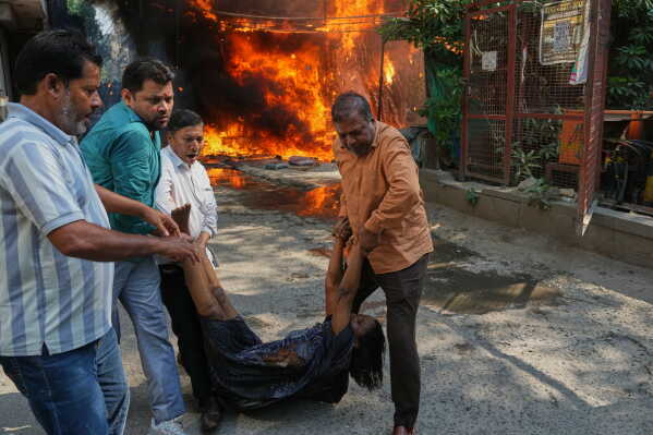 Local people rescue a foreign national from a hotel fire in New Delhi, India, Wednesday, June 3, 2026. (AP Photo/Manish Swarup)