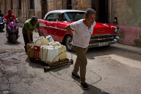 People transport containers of water in Havana, Wednesday, June 3, 2026. (AP Photo/Ramon Espinosa)