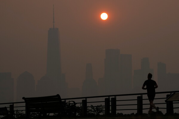 A man runs in front of the sun rising over the lower Manhattan skyline in Jersey City, N.J., June 8, 2023. (AP Photo/Seth Wenig, File)