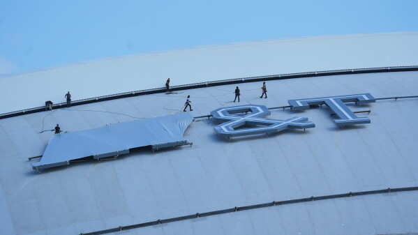 Workers cover signage on the exterior of AT&T Stadium, which will be named Dallas Stadium during the 2026 FIFA World Cup soccer tournament, as preparations continue at the venue, Tuesday, June 2, 2026, in Arlington. (AP Photo/LM Otero)