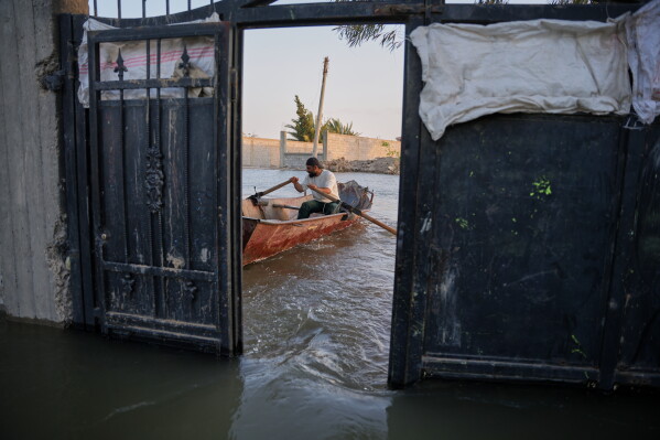 A resident rows a small boat through floodwaters outside a submerged home along the banks of the Euphrates River near Deir ez-Zor, Syria, Friday, May 29, 2026. (AP Photo/Omar Albam)