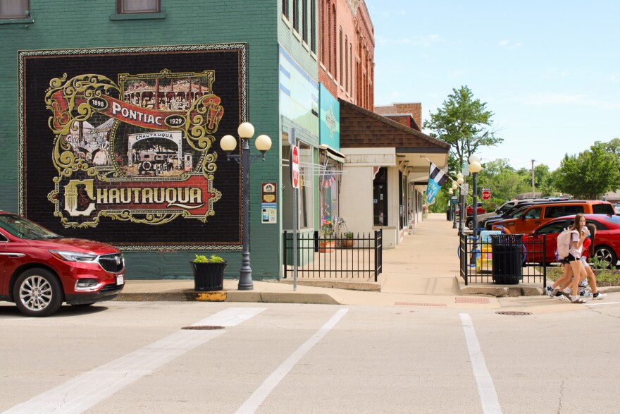A small town main street intersection with a colorful mural painted on a teal green brick wall.