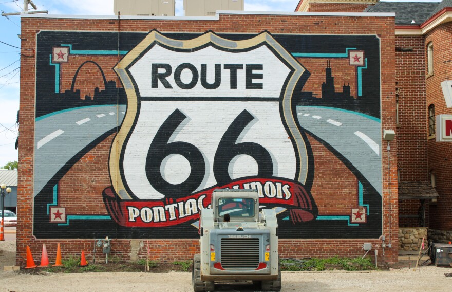 A large mural of the Route 66 shield is partially covered by a construction vehicle and orange cones.