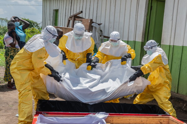 Red Cross workers carry the body of a person who died of Ebola into a coffin at a health center in Rwampara, Congo, Wednesday, May 20, 2026. (AP Photo/Moses Sawasawa)
