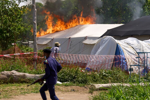 A security guard runs in front of an Ebola treatment center in flames in Rwampara, Congo, Thursday, May 21, 2026. (AP Photo/Dirole Lotsima Dieudonne)