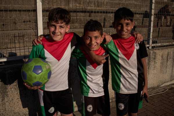Wearing jerseys in the colors of the Palestinian flag, boys smile as they pose after taking part in a soccer practice session at the municipal stadium in the West Bank city of Nablus, Thursday, May 7, 2026. (AP Photo/Leo Correa)