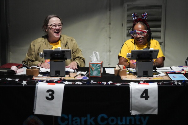 Election workers Natosha Muhidin, right, and Barbara Wolfe laugh while working at a primary voting center set up in a tent in Las Vegas, Tuesday, June 9, 2026. (AP Photo/Jae C. Hong)