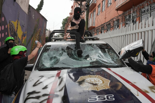 Demonstrators damage a police car during a march near the stadium during the opening match of the 2026 FIFA World Cup in Mexico City, Thursday, June 11, 2026. (AP Photo/Alejandro Cegarra)