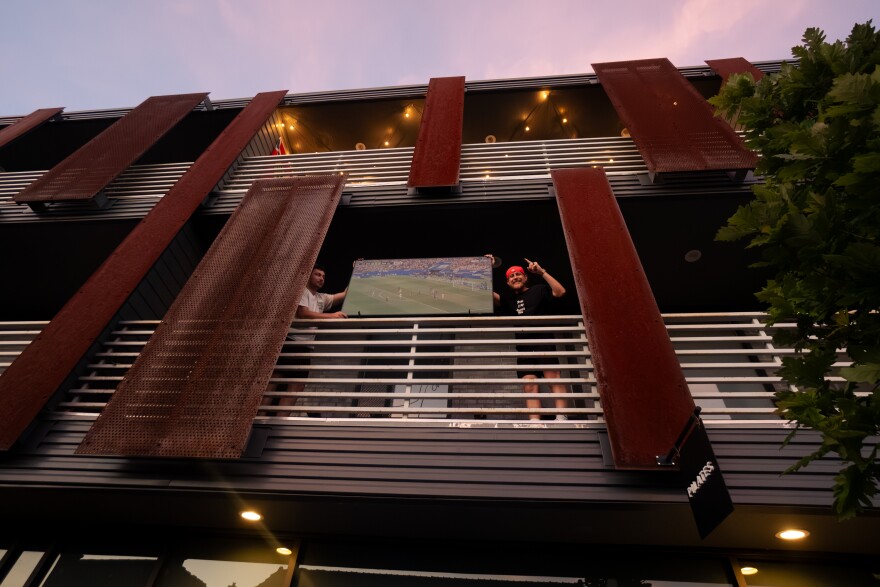 Connor McDonald, left, and Cole Kline hold up a television outside their friend Matt Waller’s apartment (not pictured) after an outdoor FIFA World Cup watch party’s stream cut due to a power issue on Friday, June 12, 2026, outside of Amsterdam Tavern in south St. Louis.
