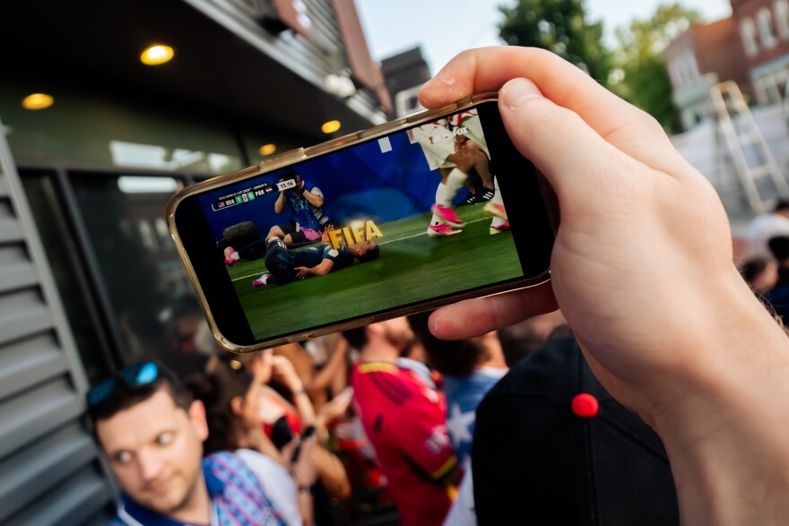 United States fans watch the USMNT take on Paraguay on their phones during a FIFA World Cup watch party outside of Amsterdam Tavern on Friday, June 12, 2026, in south St. Louis. Moments prior, the outdoor watch party’s stream cut due to a power issue.
