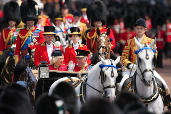 Britain's King Charles III waves to the crowd along side Queen Camilla as they return to Buckingham Palace during Trooping The Colour, the King's annual birthday parade, in London, Saturday, June 13, 2026. (AP Photo/Kirsty Wigglesworth)