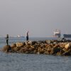 In this picture obtained from Iran's ISNA news agency on June 8, 2026, residents fish from the shore as cargo and commercial vessels lie at anchor in the Strait of Hormuz off Bandar Abbas on June 8, 2026.