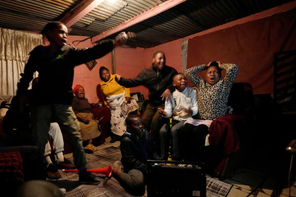 A family watches a world cup opening soccer match, in Vereeniging, South Africa, Thursday, June 11, 2026. (AP Photo/Themba Hadebe)
