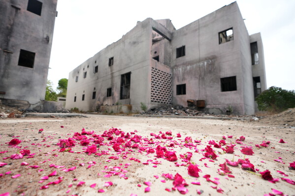 Flowers put up by the family of a victim are seen near a damaged building at the site of the June 12, 2025 Air India plane crash, in Ahmedabad, India, Thursday, June 11, 2026. (AP Photo/Ajit Solanki)