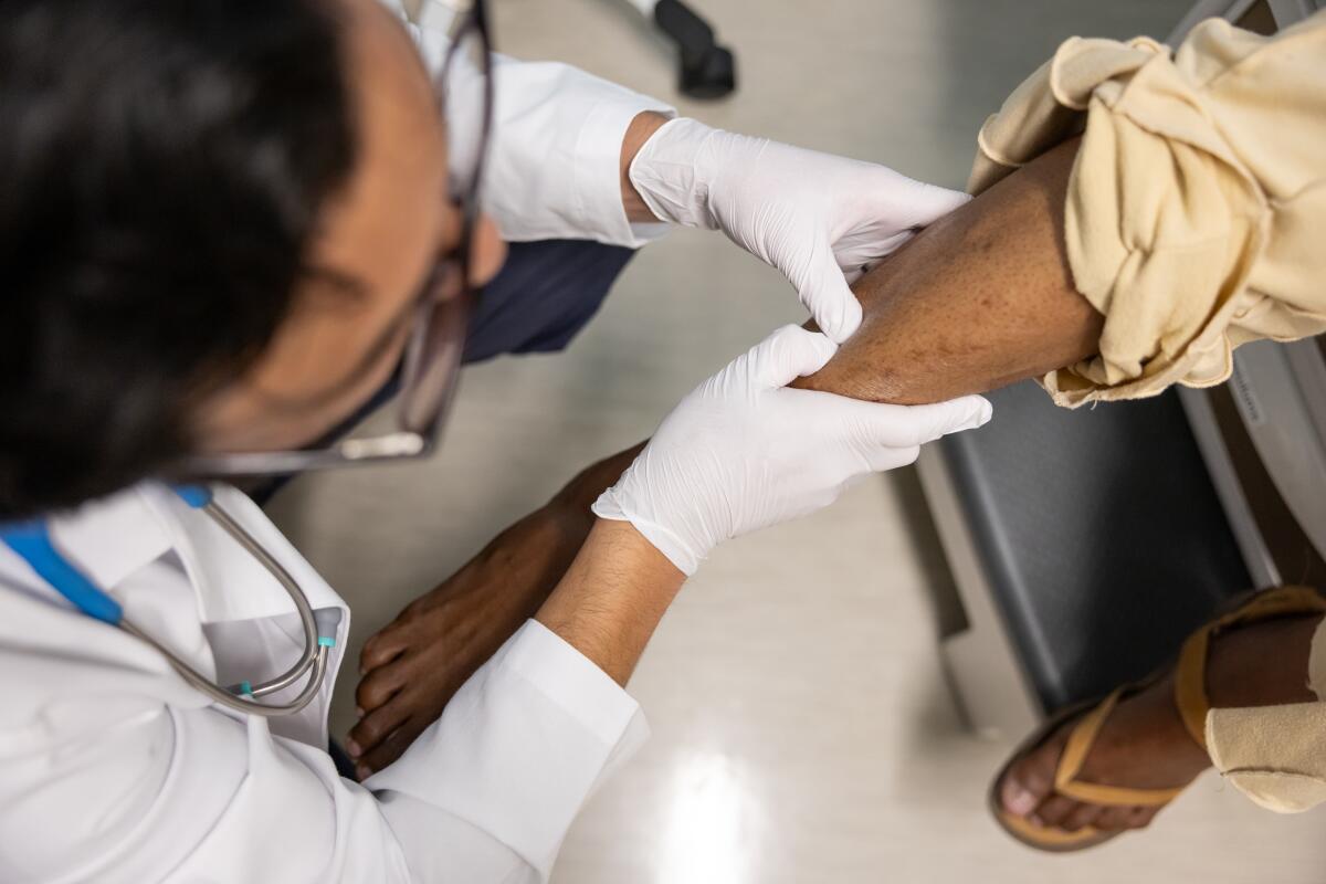 A doctor examines the leg of a patient.