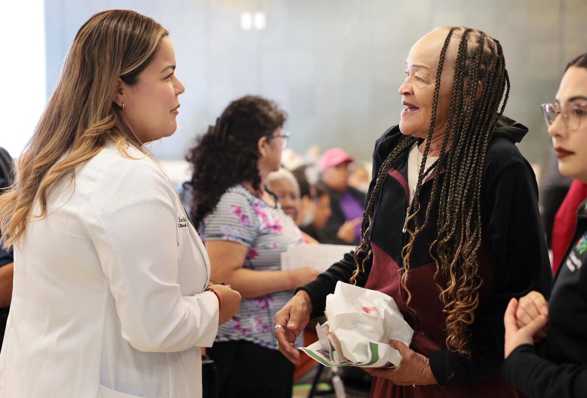 A health worker in a white lab coat talks with a patient.