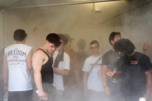 Attendees cool off in a mist tent at the UFC Fan Fest on the White House Ellipse ahead of Sunday's fight on the South Lawn, Saturday, June 13, 2026, in Washington. (AP Photo/Allison Robbert)
