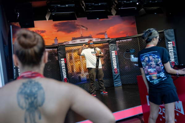 An attendee holds up a championship belt at the UFC Fan Fest on the White House Ellipse ahead of Sunday's fight on the South Lawn, Saturday, June 13, 2026, in Washington. (AP Photo/Allison Robbert)