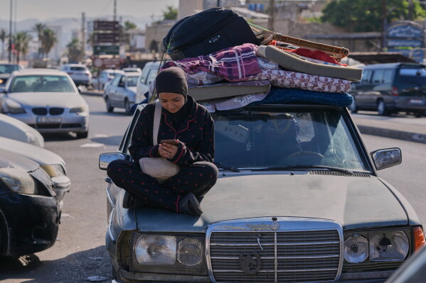 A displaced woman checks her mobile phone as she waits to return to her village following the announcement of an initial ceasefire agreement between the United States and Iran, in the southern port city of Sidon, Lebanon, Monday, June 15, 2026. (AP Photo/Mohammed Zaatari)