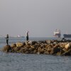 In this picture obtained from Iran's ISNA news agency, residents fish from the shore as cargo and commercial vessels lie at anchor in the Strait of Hormuz off Bandar Abbas on June 8.