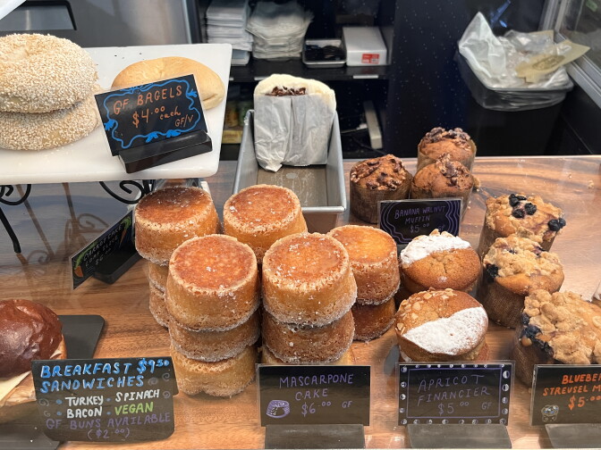 An array of delicious looking pastries and baked goods, including muffins, bagels and breakfast sandwiches.
