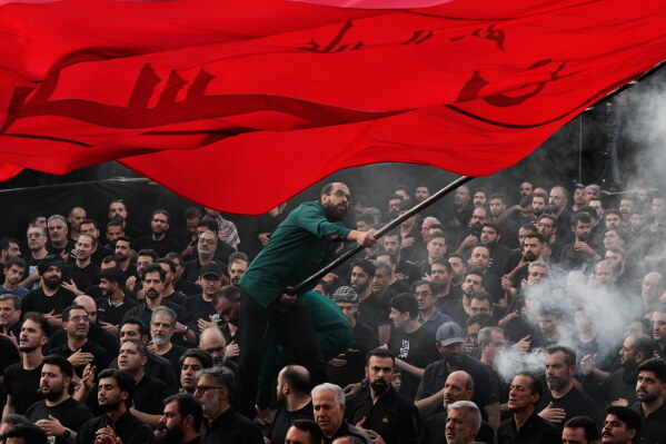 A man waves a religious flag as people beat their chests during a mourning ceremony in Tehran, Iran, Thursday, June 18, 2026, ahead of Ashoura, which honors the 7th-century martyrdom of the Prophet Muhammad's grandson, Hussein, who was killed in a battle in Karbala in present-day Iraq. (AP Photo/Vahid Salemi)