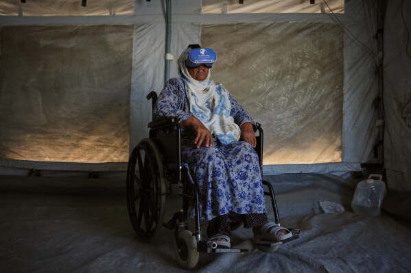Khadija Al-Ladawi, 71, participates in a psychological support session using a virtual reality headset in a tent operated by a medical technology team in Zawaida, central Gaza Strip, Wednesday, June 17, 2026. (AP Photo/Abdel Kareem Hana).