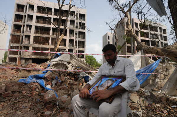 Gunjan Chaudhary holds a photograph of his wife, a victim of the Air India plane crash, on the first anniversary of the crash at the crash site in Ahmedabad, India, Friday, June 12, 2026. (AP Photo/Ajit Solanki)