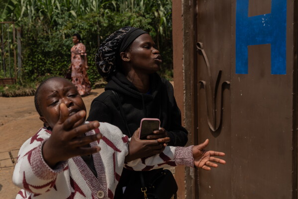 Relatives of Angèle Muyumba Nsimire, a university student who died of Ebola, react at the Citadelle Clinic as health workers prepare her body for burial in Bunia, Congo, Friday, June 12, 2026. (AP Photo/Moses Sawasawa)