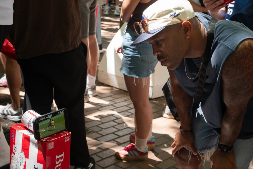 In Pioneer Square, Jordan Smith watches the U.S. play Australia in the World Cup on a phone rather than try to fight the crowds. June 19, 2026.