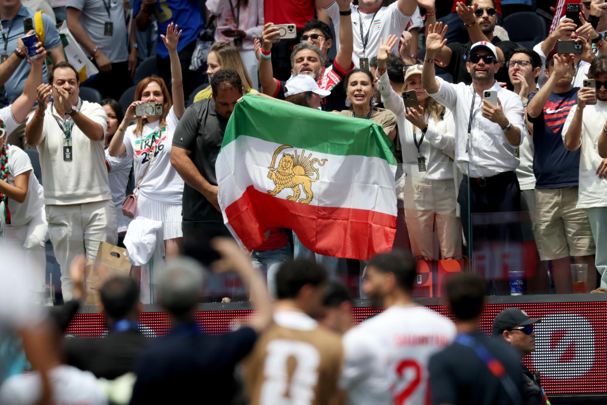 Iranian soccer fans hold a pre-revolutionary Iranian flag following the team's scoreless draw.