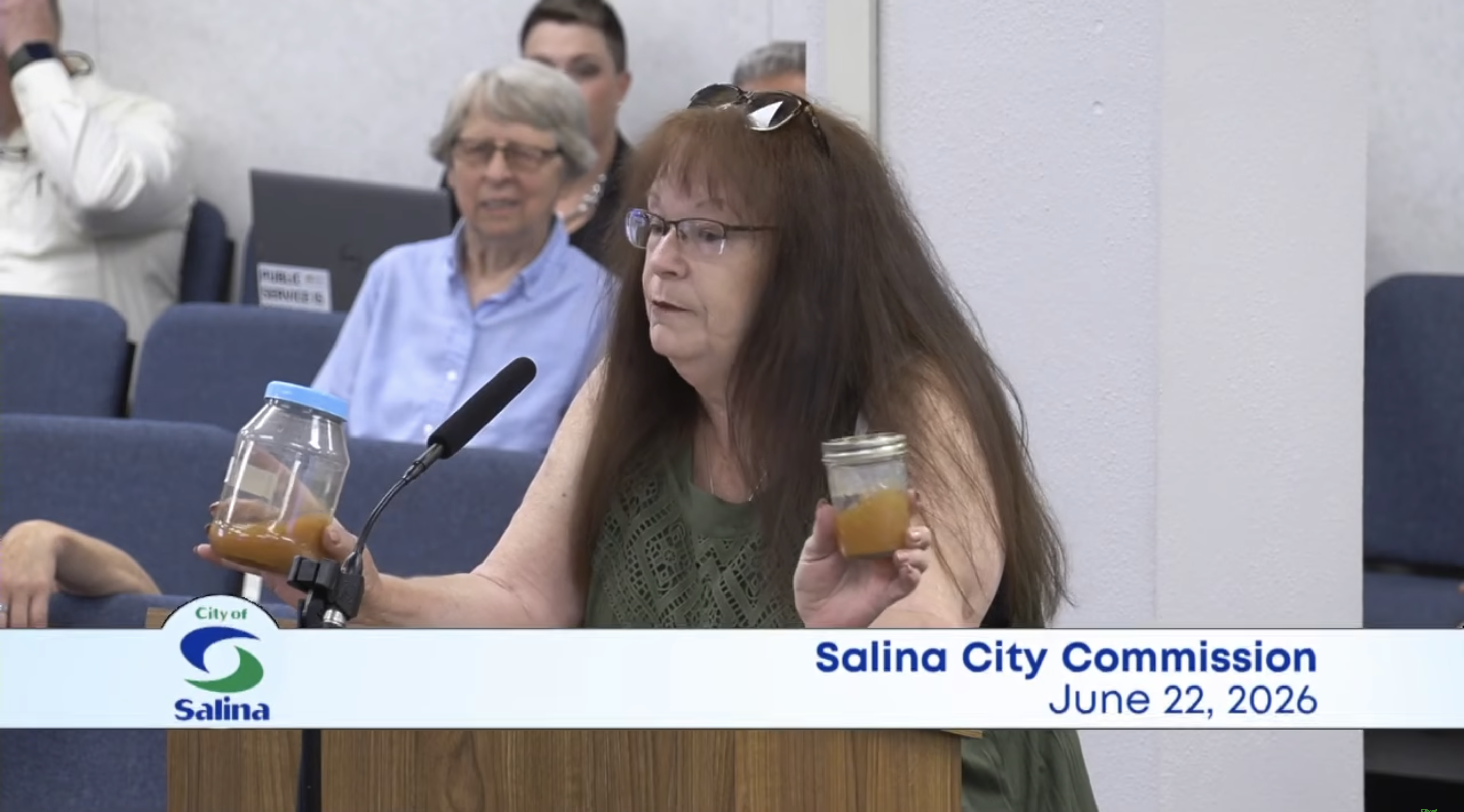 Dover Drive resident Sheree Spratlen shows two containers of discolored water Salina Commissioners on June 22 - Screenshot of Salina City Commission public meeting 