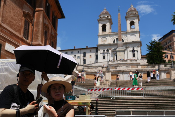 Tourists use umbrellas to shelter from the sun as they visit the historical Spanish steps in Rome, Tuesday, June 23, 2026. (AP Photo/Alessandra Tarantino)