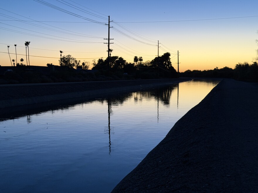 Blurred silhouettes of bats can be seen against a sunset view of a gently rippling canal in Phoenix