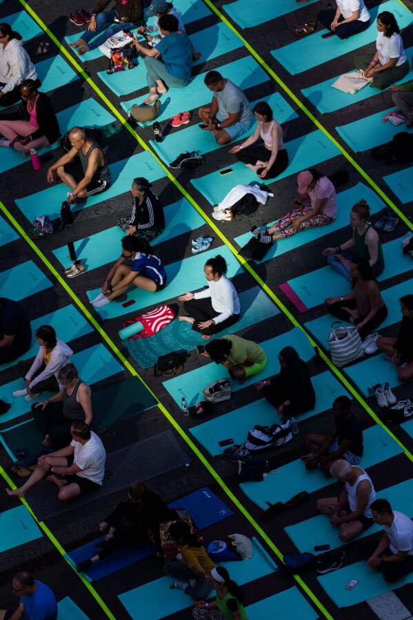 People participate in a mass yoga class during the "Times Square: Mind Over Madness Yoga" event, to celebrate the summer solstice, Sunday, June. 21, 2026, in New York (AP Photo/Adam Gray)