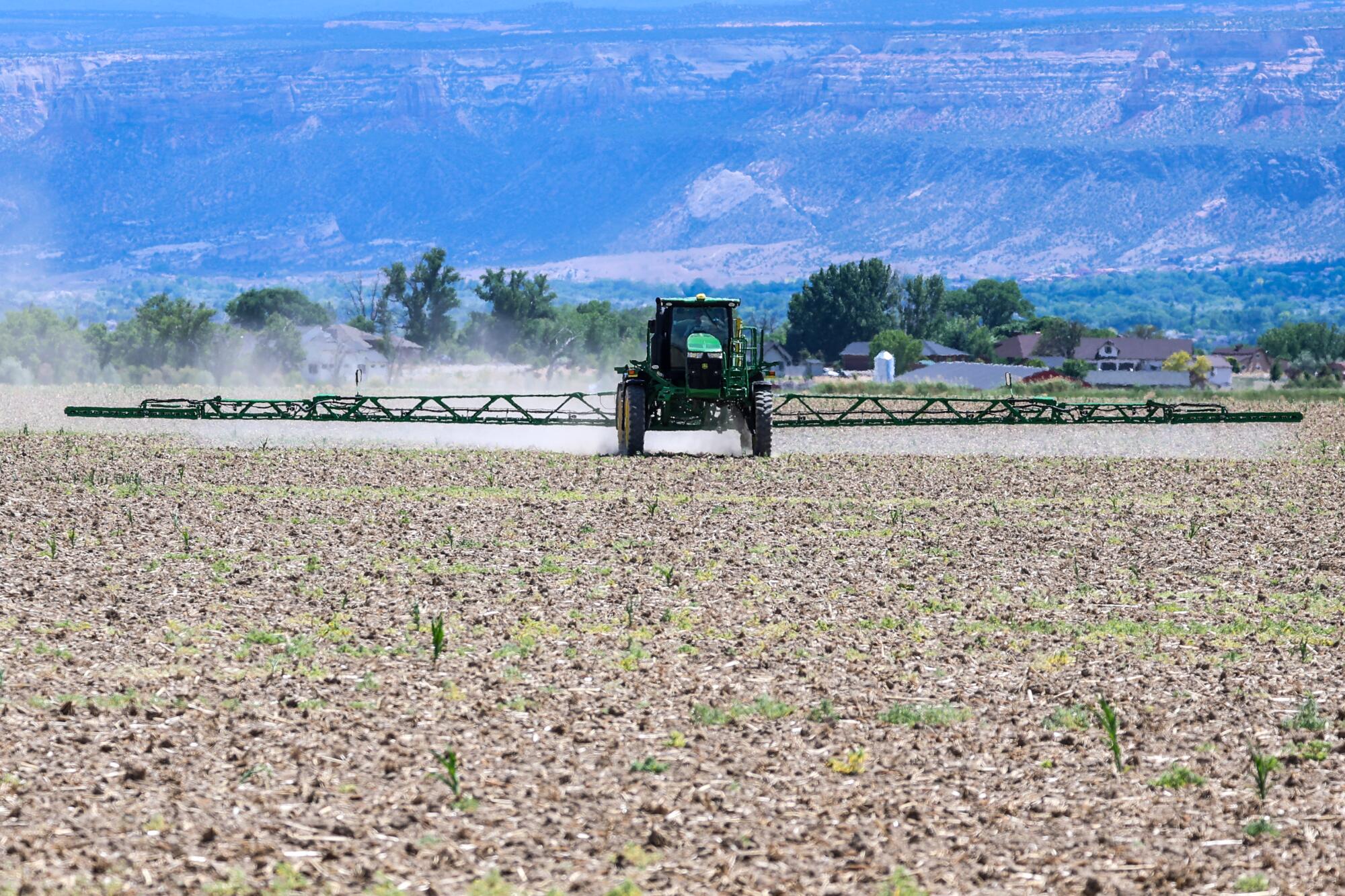 A tractor spraying herbicide on a field