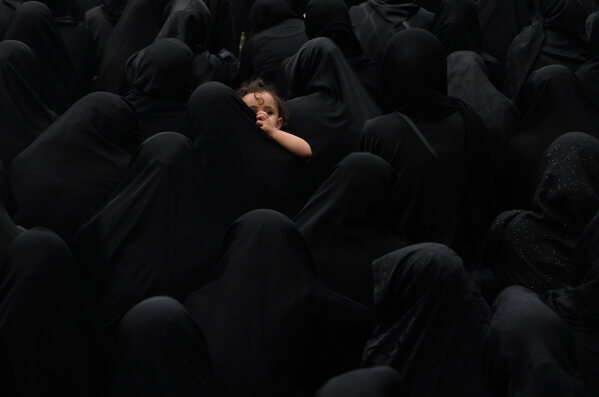 A woman holds a child during a mourning ceremony in Tehran, Iran, Thursday, June 25, 2026, in the holy day of Ashoura which commemorates the martyrdom of Imam Hussein, a grandson of the Prophet Muhammad, and his family and companions at the Battle of Karbala in A.D. 680, in present-day Iraq, after refusing to pledge allegiance to the Umayyad caliphate. (AP Photo/Vahid Salemi)