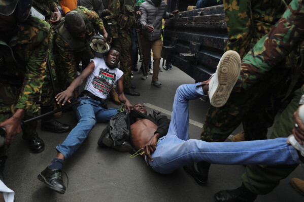 Kenyan police officers arrest protesters near parliament during a demonstration to mark two years since more than 60 people died in anti-government protest that resulted in the storming of the parliament, Nairobi, Kenya, Thursday, June 25, 2026. (AP Photo/Henry Naminde)